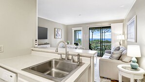 Una cocina moderna con un lavamanos de acero inoxidable, un comedor con vistas y una zona de estar acogedora con una lámpara.
