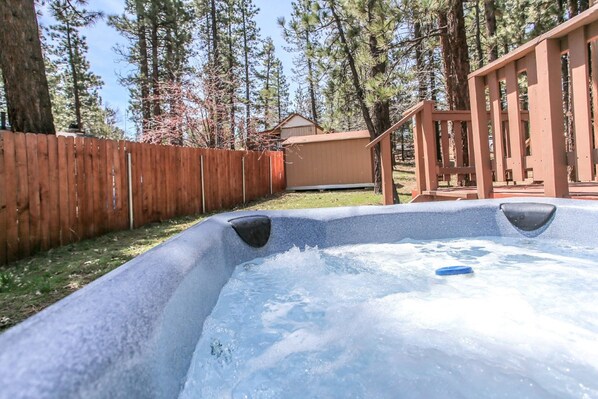 Ein Whirlpool in einem Garten mit einer Holzterrasse und einem Holzzaun.