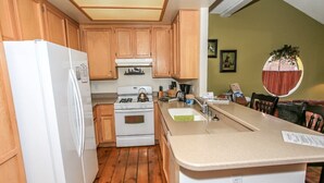Una cocina compacta con armarios de madera, un refrigerador blanco, una estufa y un lavamanos.