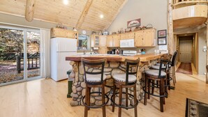 Een keuken met houten kastjes, een stenen muur en een bar met krukken.