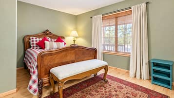 Un dormitorio con cama de madera, un banco, una ventana con cortinas y una lámpara.