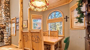 Una mesa de comedor de madera con sillas, una lámpara de techo de vitral y una pared de piedra.