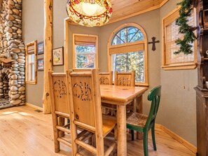 Una mesa de comedor de madera con sillas, una lámpara de techo de vitral y una pared de piedra.