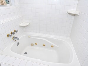 Una bañera blanca con múltiples grifos y un estante integrado.
