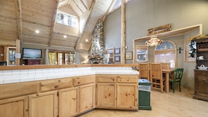Een ruime keuken met houten kastjes, een stenen openhaard en een groot kookeiland.