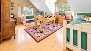 Un dormitorio acogedor en el ático con una cama de madera, una mesa de f útbol, un escritorio y una ventana con vistas.
