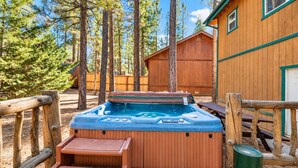 Una terraza de madera con un jacuzzi, bancos de madera y un bote de basura.