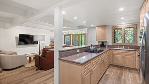A modern kitchen with wooden cabinets, a granite countertop, and a built-in stove.