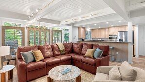 A modern living room with a sectional sofa, a coffee table, and a kitchen in the background.