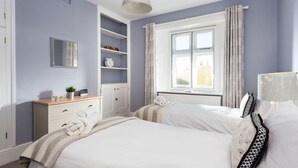 A bedroom with a bed, a dresser, a mirror, and a window with curtains.