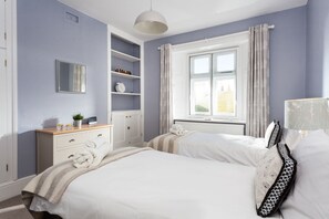 A bedroom with a bed, a dresser, a mirror, and a window with curtains.