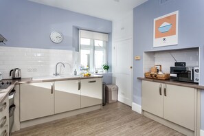 A modern kitchen with white cabinets, a stainless steel sink, and a microwave.