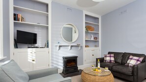 A living room with a television, sofa, armchair, fireplace, and a round coffee table.