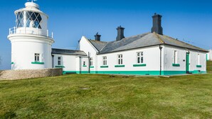 A lighthouse with a white tower and a white building with green trim.