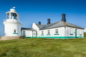 A lighthouse with a white tower and a white building with green trim.