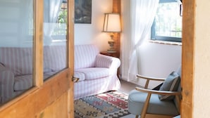 A cozy room with a wooden ceiling, a pink-striped sofa, a blue armchair, a patterned rug, and a lamp. - Vacation home La Vigna with Pool (San Toma')