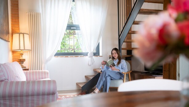 A cozy living room with a sofa, a table, and a person reading a book. - Vacation home La Vigna with Pool (San Toma')