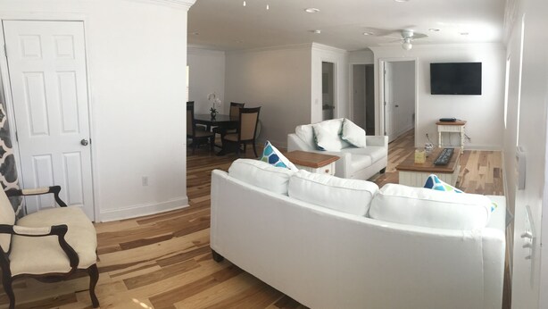 A living room with a white sofa, a wooden dining table with chairs, and a white armchair. - Alecia B&B (Atlanta)