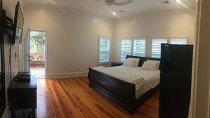 A bedroom with a wooden floor, a bed with white bedding, a nightstand, and a black dresser. - Alecia B&B (Atlanta)