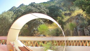 A sun lounger with a curved canopy, a wicker side table with a bowl of fruit, and a cushion. - The cortijo, a spacious, beautifully designed holiday home & pool in Extremadura (Caceres)