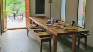 A dining area with a long wooden table, benches, and a view of greenery outside. - The cortijo, a spacious, beautifully designed holiday home & pool in Extremadura (Caceres)