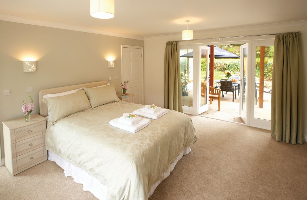 Ground floor:  Bedroom with a 5' bed and doors to outdoor patio area with separate seating. The cloakroom with shower is also accessible from this bedroom