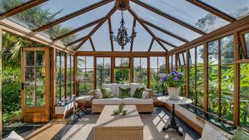 A conservatory with a glass ceiling, a sofa, a table, and a chandelier.