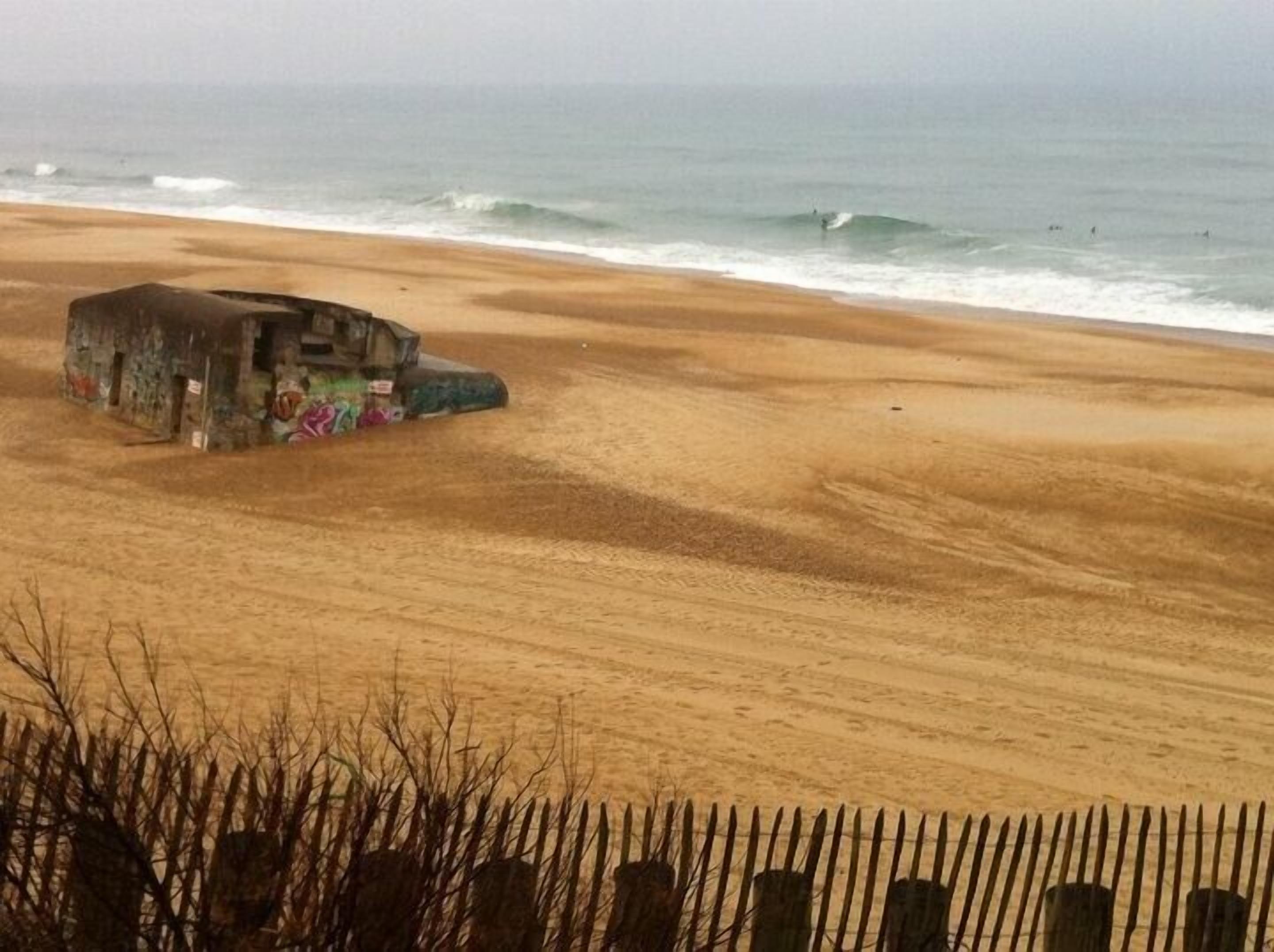 A beach with a dilapidated structure covered in graffiti.