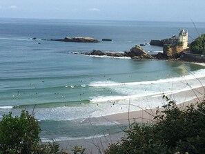 A coastal view with a beach, waves, and a castle-like structure.