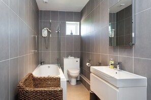 A modern bathroom with a bathtub, toilet, and sink.