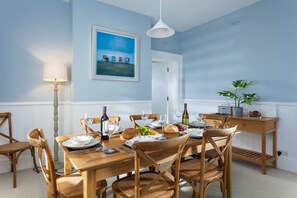 A dining room with a wooden table set for six, surrounded by six wooden chairs.