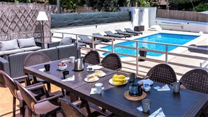 A poolside dining area with a table set for two, a wicker sofa, and a pool in the background. - CHALET MONTESOL, LUXURY IN THE BEST AREA OF LA DROVA, NEXT TO GANDIA (barx)