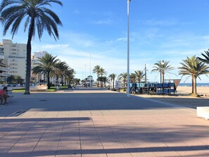 A paved promenade with palm trees, benches, and a playground. - CHALET MONTESOL, LUXURY IN THE BEST AREA OF LA DROVA, NEXT TO GANDIA (barx)