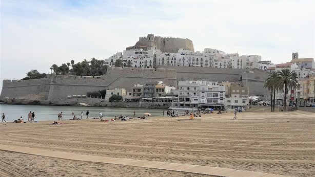 A coastal cityscape with a prominent fortress-like structure, a sandy beach, and a variety of buildings including a hotel with multiple floors and balconies. - CHALET MONTESOL, LUXURY IN THE BEST AREA OF LA DROVA, NEXT TO GANDIA (barx)