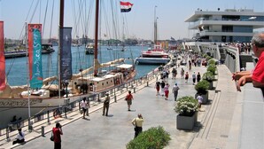 A busy waterfront promenade with people walking, a sailboat docked, and a Louis Vuitton banner. - CHALET MONTESOL, LUXURY IN THE BEST AREA OF LA DROVA, NEXT TO GANDIA (barx)