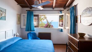 A bedroom with a bed, a chair, a dresser, and a window with curtains.