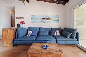 Un salon avec un canapé bleu, une table basse en bois et un tableau représentant un moulin à vent accroché au mur.