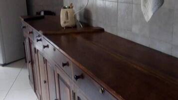 A kitchen with a wooden countertop, cabinets, and a towel hanging on the wall.