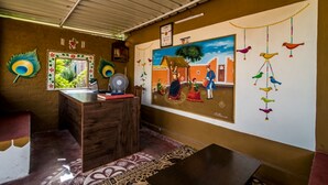Quarto com escrivaninha de madeira, tapete estampado, painel decorativo e ventoinha no teto.