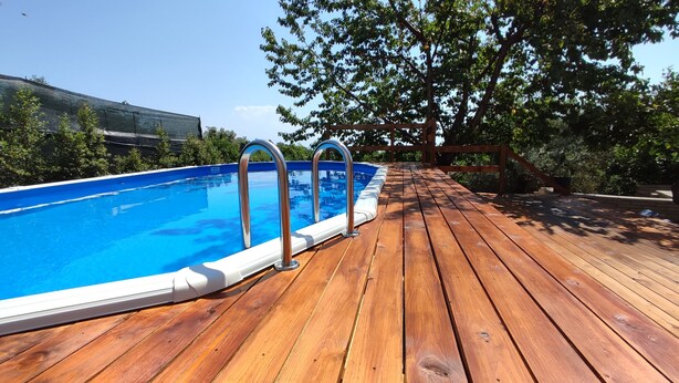 Eine Holzterrasse mit Schwimmbecken und Metallleitern.