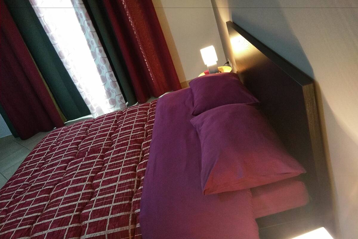 A hotel room with a bed, curtains, and a bedside lamp.