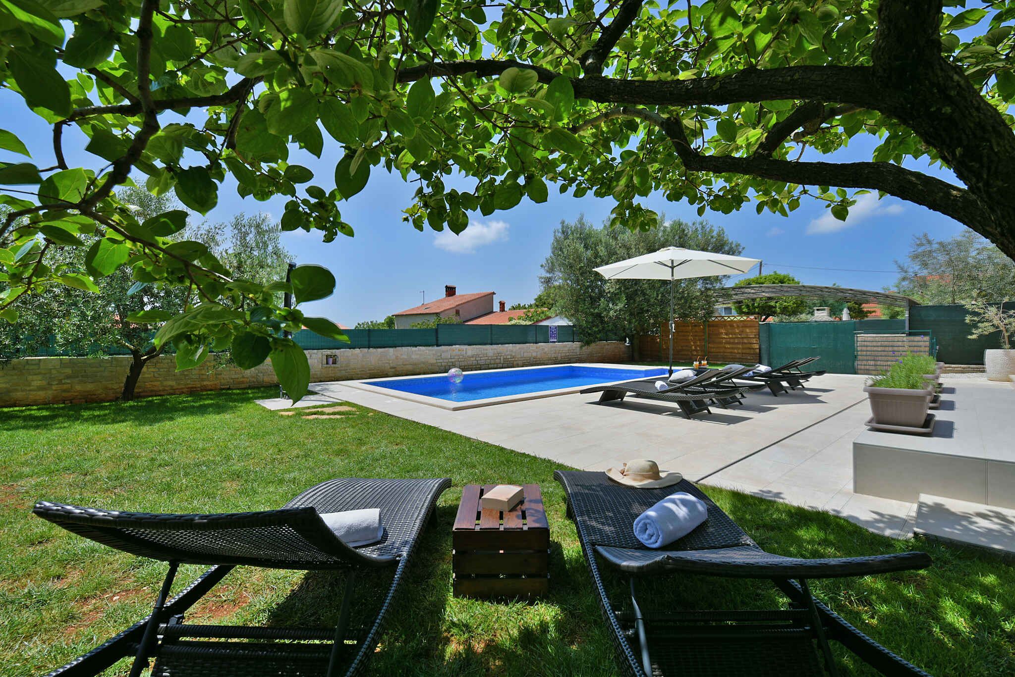A backyard with a swimming pool, lounge chairs, and a patio area.