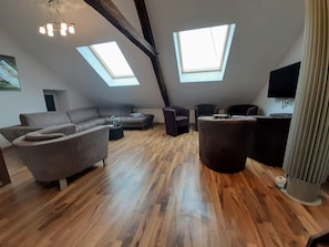 A spacious loft with high ceilings, exposed beams, and skylights.