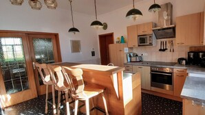 Una cocina moderna con armarios de madera, electrodomésticos de acero inoxidable y una barra con taburetes.