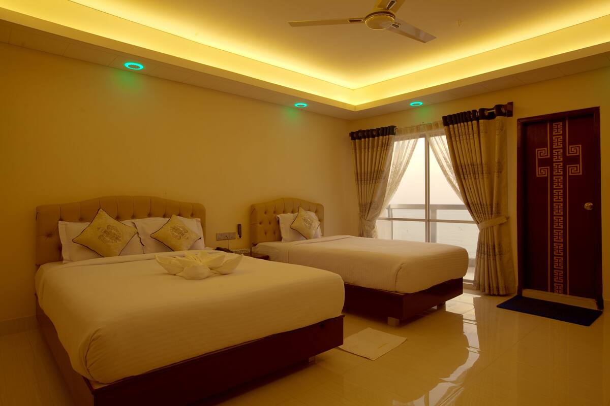 A hotel room with two beds, a ceiling fan, and a large window with curtains.