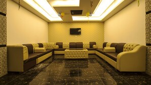 A modern living room with a sectional sofa, a flat-screen TV, and a patterned wall. - Exotica Sampan (Cox's Bazar)
