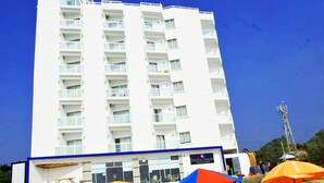 A multi-story hotel with balconies, a storefront, and a clear blue sky. - Exotica Sampan (Cox's Bazar)