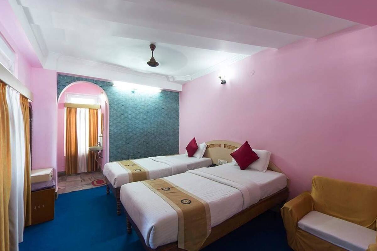 Une chambre d’hôtel avec deux lits, un canapé, une petite salle de bain et un arc décoratif.