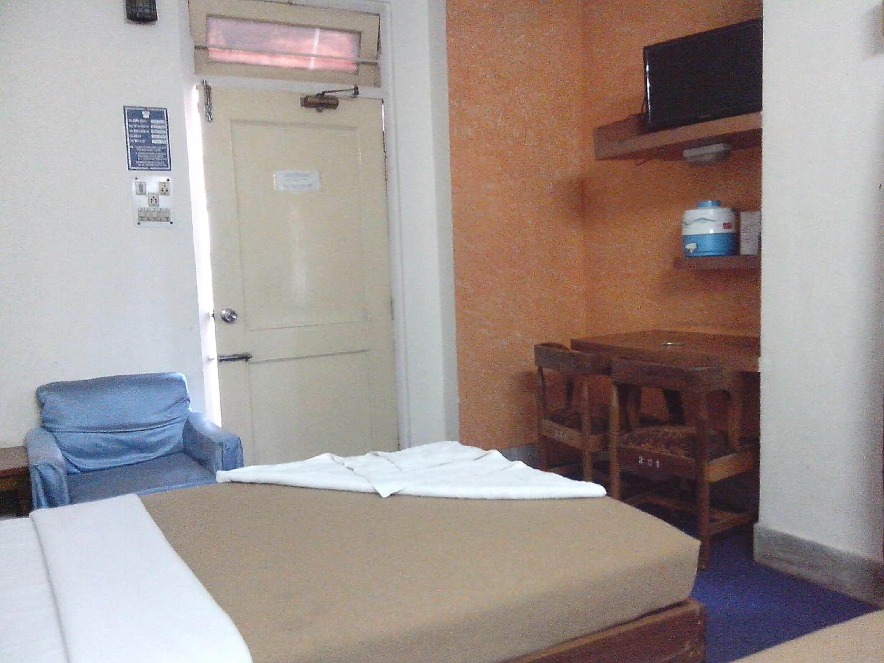 Una habitación con cama, una silla, un escritorio y una televisión.