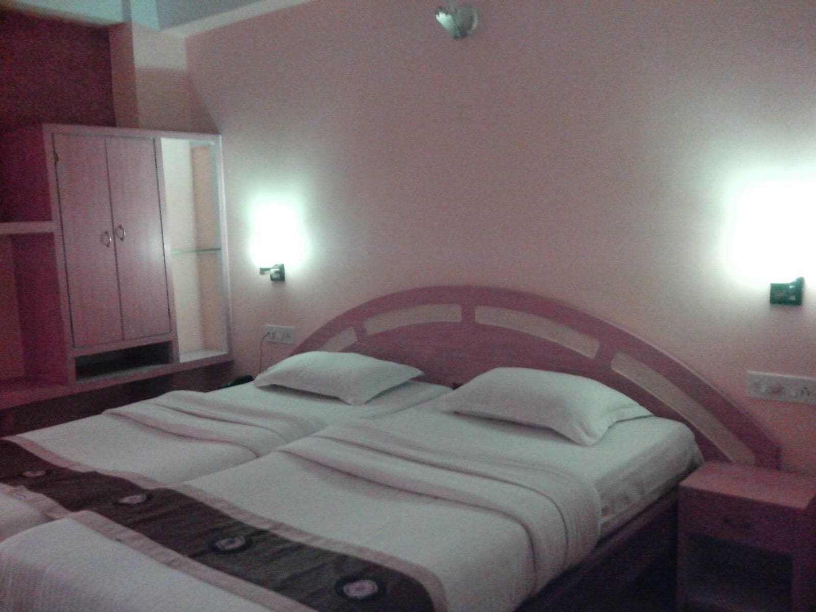 Una cama doble con cabecera de madera, mesita de noche y armario.